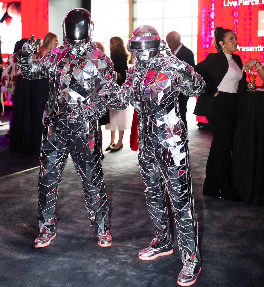 Two people dressed in mirror ball suits posing as statues during reception.